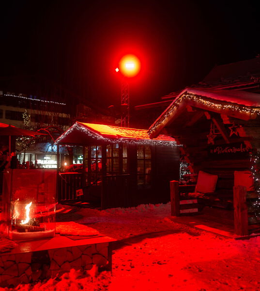 Nächtlicher Winterzauber-Markt mit beleuchteten Hütten und Feuerstelle