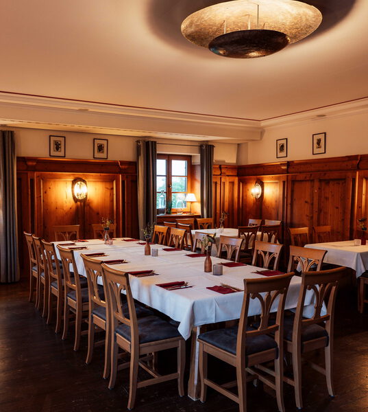 Nebenzimmer im Fischers Mohrenplatz mit langer festlich gedeckter Tafel, weißen Tischdecken und roten Servietten unter einer großen Messing-Deckenleuchte
