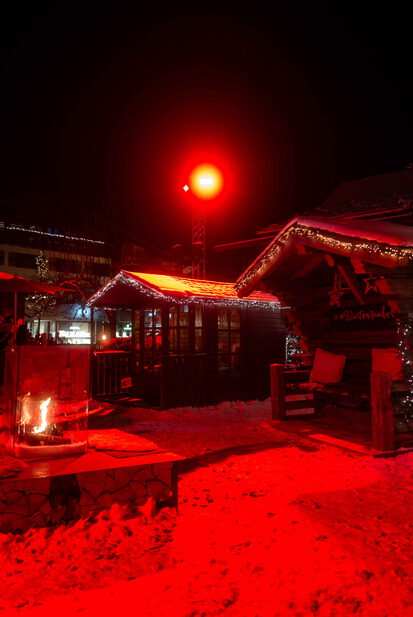 Nächtlicher Winterzauber-Markt mit beleuchteten Hütten und Feuerstelle